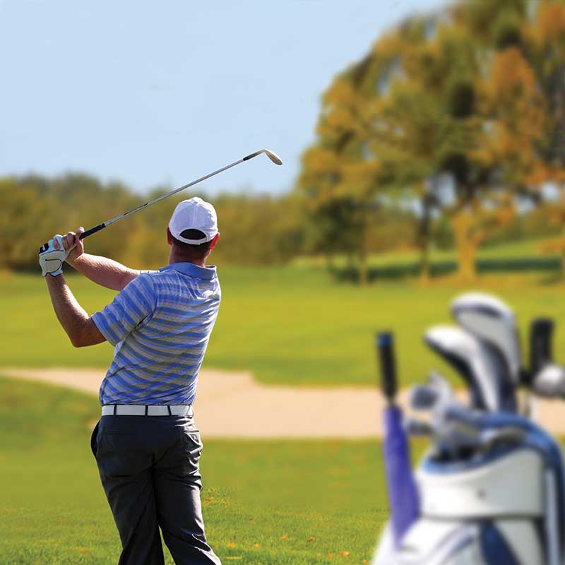 golf bag with man holding a golf club in background